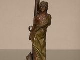 statue en bronze représentant une femme tenant une épée posée sur une table