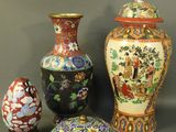 trois vases et un œuf posés sur une table, sur fond gris