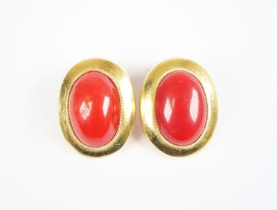 a pair of red and gold earrings on a white surface