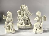 three white figurines of angels sitting on top of a table