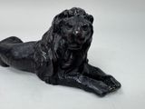 a statue of a lion laying down on a white surface