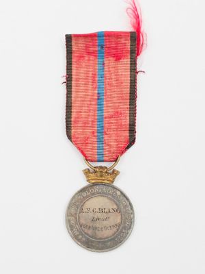 une vieille médaille ornée d'un ruban rouge, bleu et noir sur fond blanc