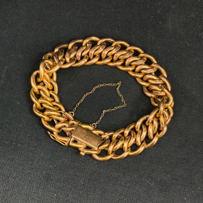 une image représentant un bracelet à chaîne en or muni d'un fermoir, sur fond noir