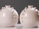 deux vases blancs posés sur une table, sur fond gris