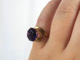 someone is holding a ring with a purple stone on it