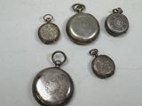 four silver pocket watches and a silver coin on a white surface