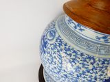 un vase bleu et blanc muni d'un couvercle en bois, posé sur un socle
