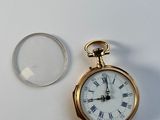 une montre de poche en or avec des chiffres romains et une loupe