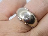a man ' s hand holding a silver ring with a diamond on it