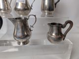 three silver pitchers on display in a glass case