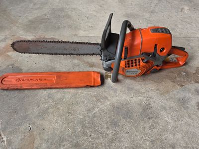 une tronçonneuse orange posée par terre à côté d'une tronçonneuse orange