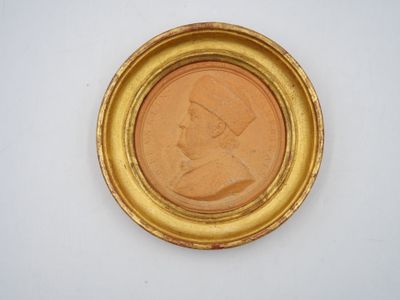 a close up of a coin in a gold frame on a white surface