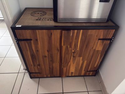 a small refrigerator with a wooden cabinet in the corner of the room