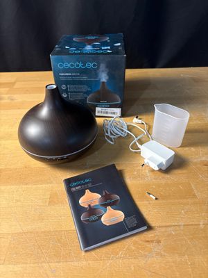 a wooden table with a lamp, a book, and a cup on it