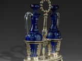 two blue glass vases on a stand with a silver base