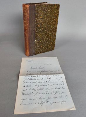 un vieux livre posé sur une table à côté d'une feuille de papier