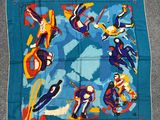 a close up of a blue scarf with a group of people flying in the sky