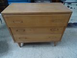 une commode en bois dans une pièce où se trouve un canapé bleu
