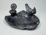 a statue of a bird sitting on top of a plate