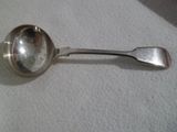 une cuillère en argent avec un manche de cuillère sur une surface blanche