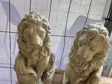 deux statues de lions posées sur une table devant une fenêtre