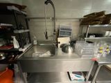 une cuisine équipée d'un évier et d'un plan de travail en métal