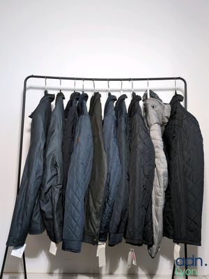 a lot of jackets hanging on a rack in a room