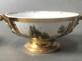a gold and white bowl with a picture of a house on it