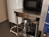 a small kitchen with a microwave on a metal stand
