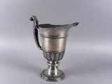 une coupe ancienne en argent avec une anse, sur fond blanc