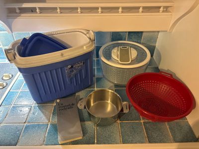 a blue and white cooler sitting on the floor next to a red and white bucket