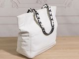white canvas tote bag with black chain handles on a wooden table