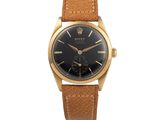 une montre-bracelet plaquée or avec un cadran noir et un bracelet en cuir marron