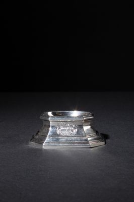 a close up of a silver candle holder on a black surface