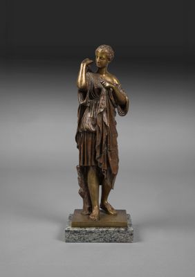 une statue en bronze représentant une femme tenant un oiseau, posée sur un socle en marbre