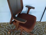 une chaise de bureau marron avec une assise marron, posée sur un tapis