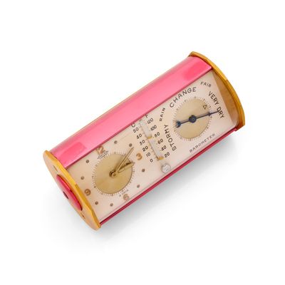 une horloge rose et dorée posée sur un support blanc