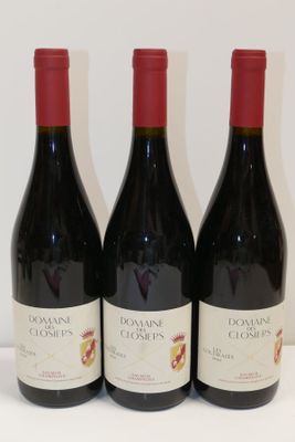 trois bouteilles de vin rouge sont alignées sur une surface blanche