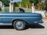 a blue convertible car parked in front of a gate