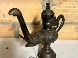 a small metal teapot with a handle on a table
