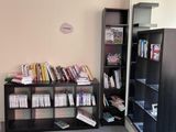 une bibliothèque dans un coin de la pièce, avec une horloge accrochée au mur