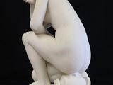 statue of a man kneeling on a white pedestal with a black background
