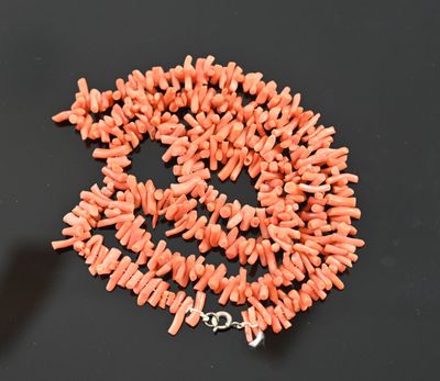 an orange coral bead necklace with a silver clasp on a black surface