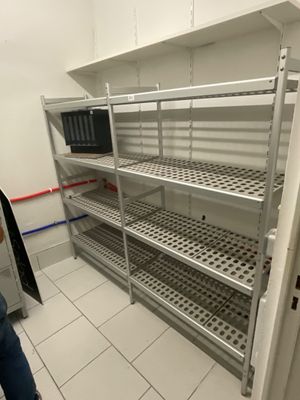 a person standing in a room with shelves and a microwave