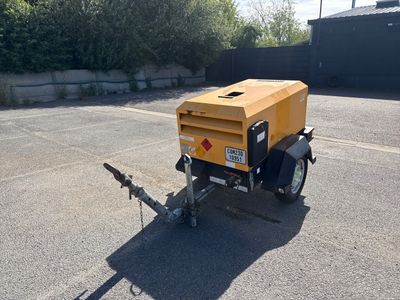 une petite remorque à laquelle est attelée une remorque jaune, sur un parking