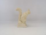 a small statue of a squirrel on a white surface