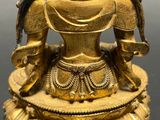 a gold statue of a woman with a bird on her shoulder