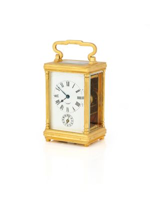 une petite horloge en or avec des chiffres romains