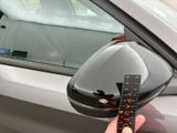 a person that is holding a remote control in front of a car
