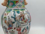 a vase with a painting on it sitting on a table